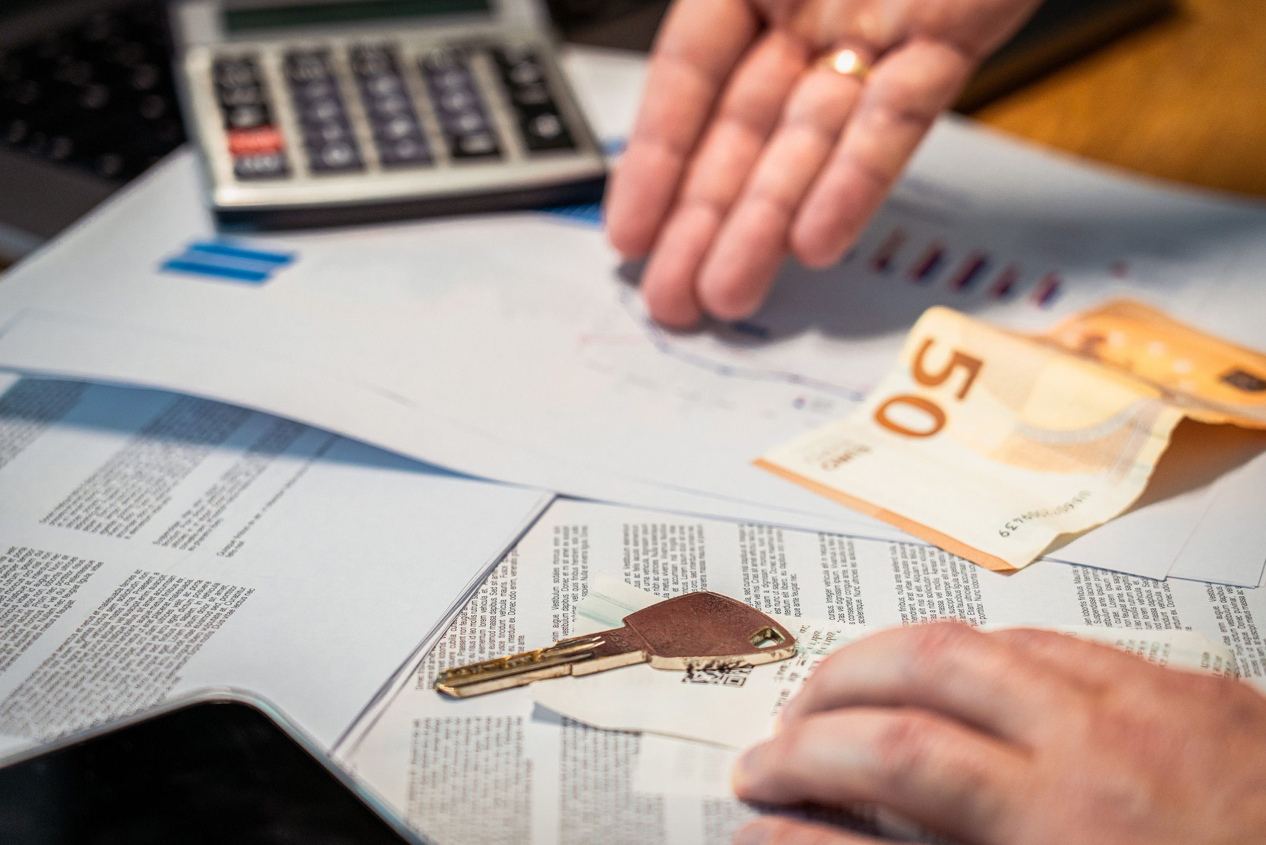 Mains examinant documents financiers, argent et clé immobilière