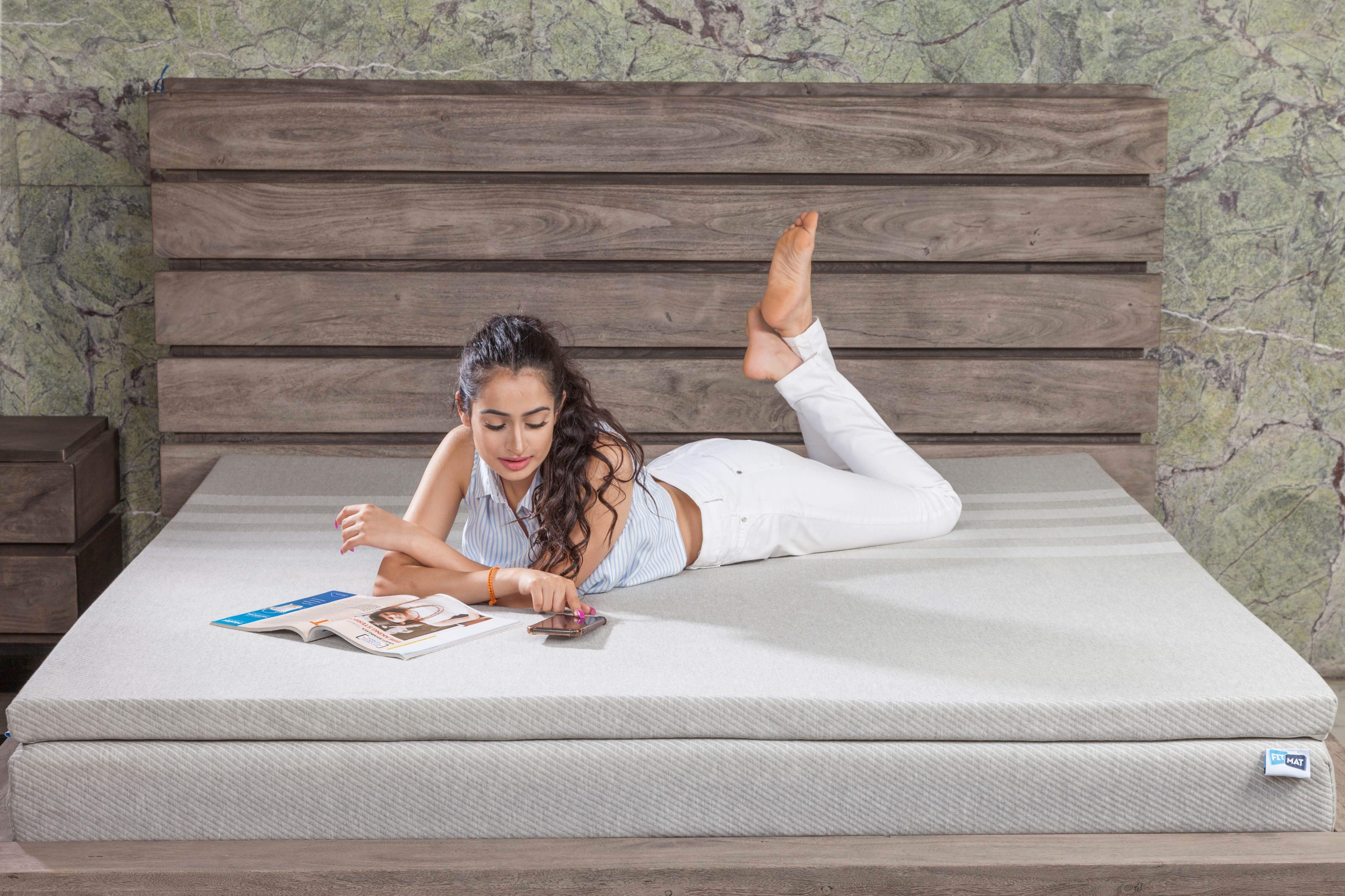 Femme détendue sur lit avec magazine et téléphone