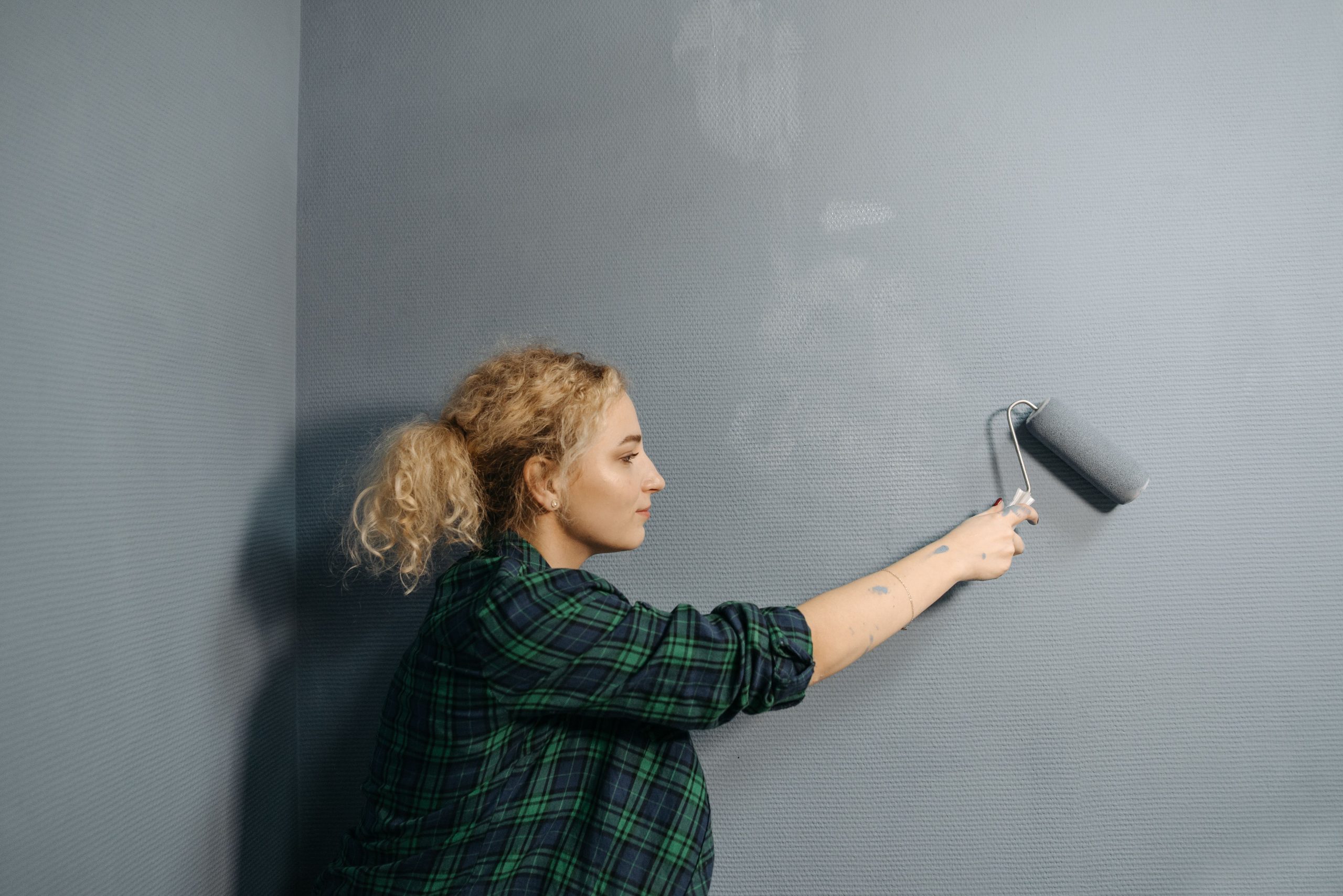 Femme appliquant peinture grise au rouleau mural