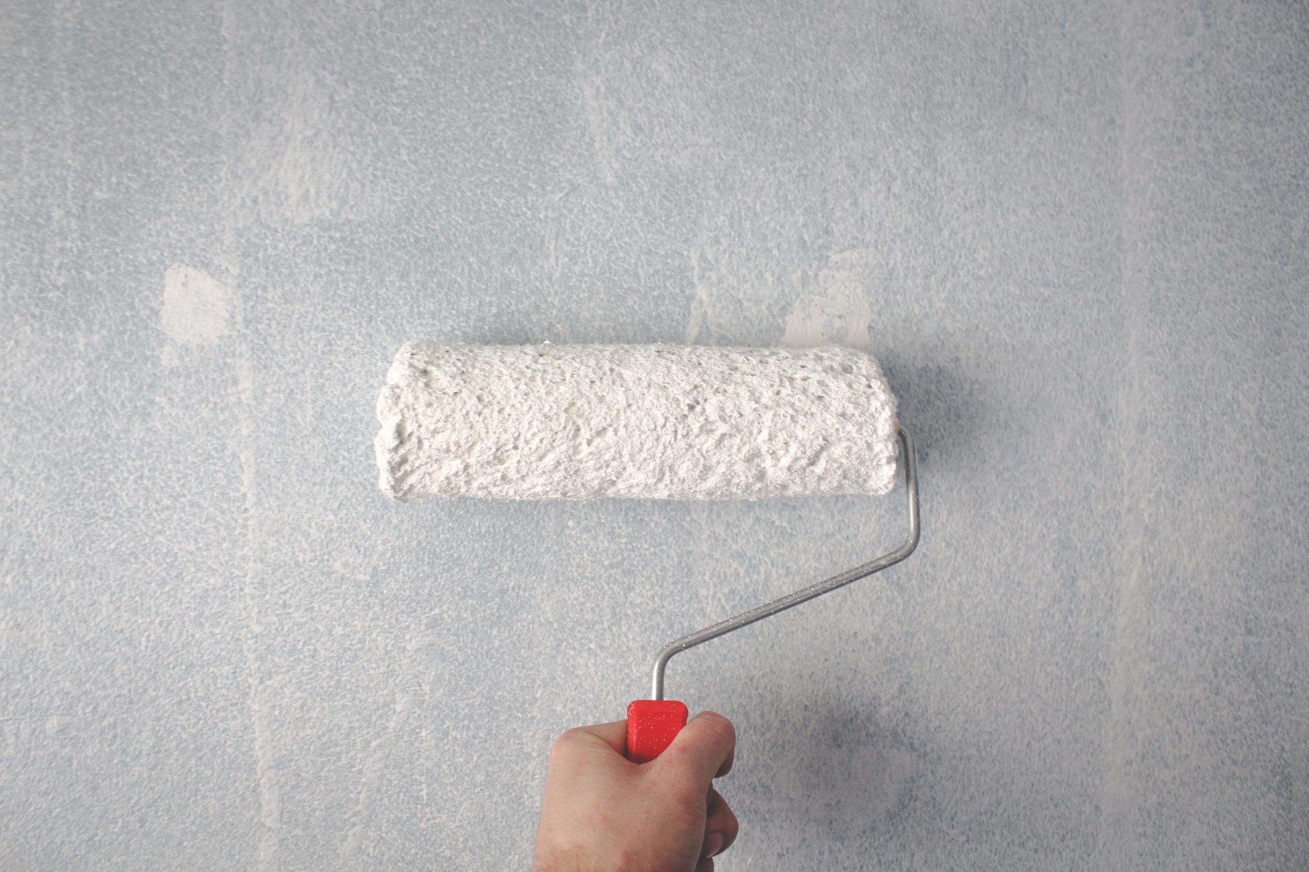 Main appliquant de la peinture blanche avec un rouleau
