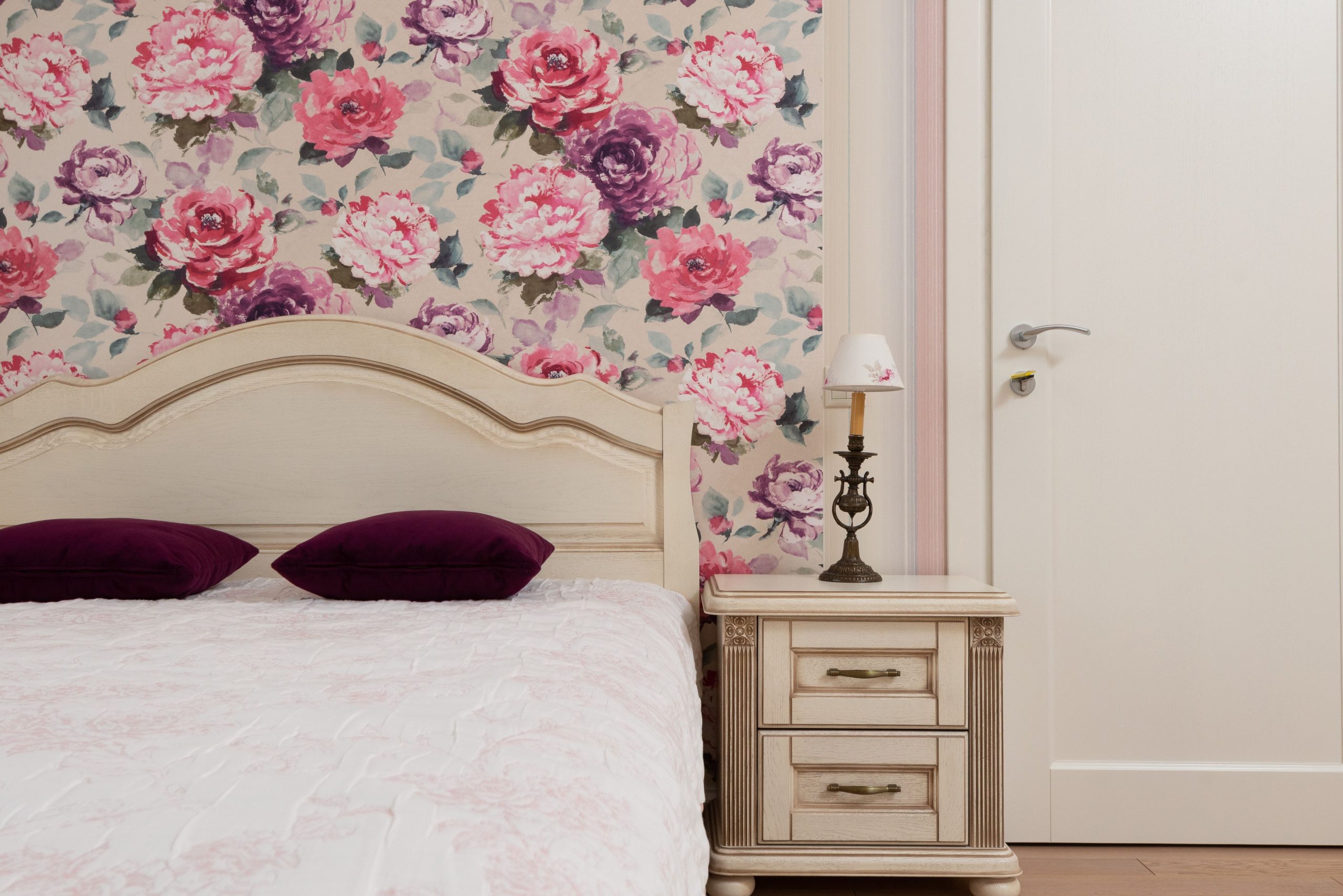 Chambre classique avec papier peint floral derrière lit